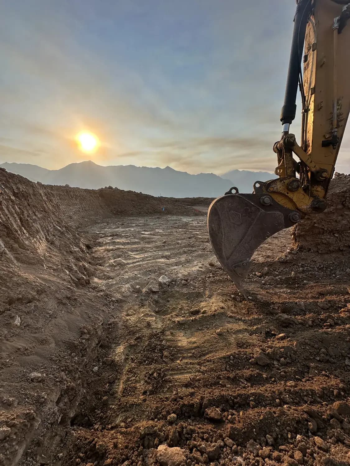 Forefront excavator working an open excavation at sunset on a Utah job site