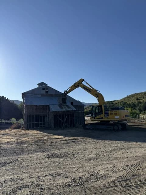 Excavator taking down a structure during demolition and site clearing