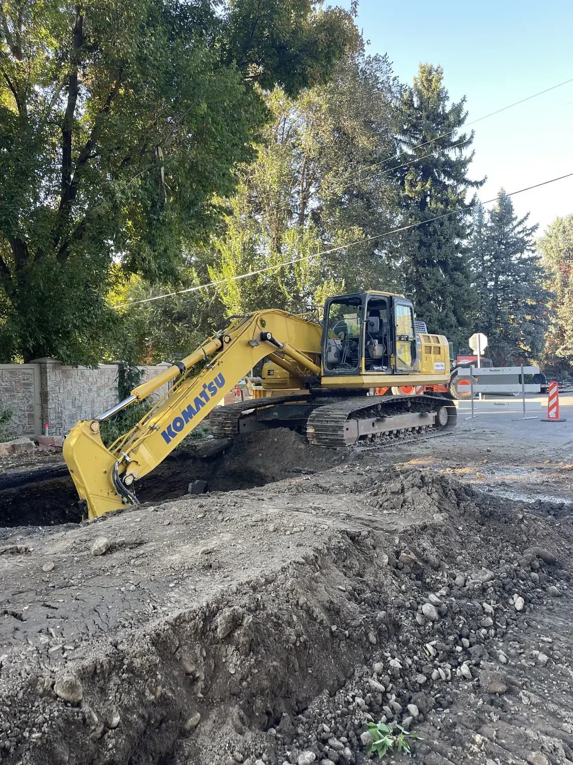 Excavator working an open street excavation with traffic control on a municipal job